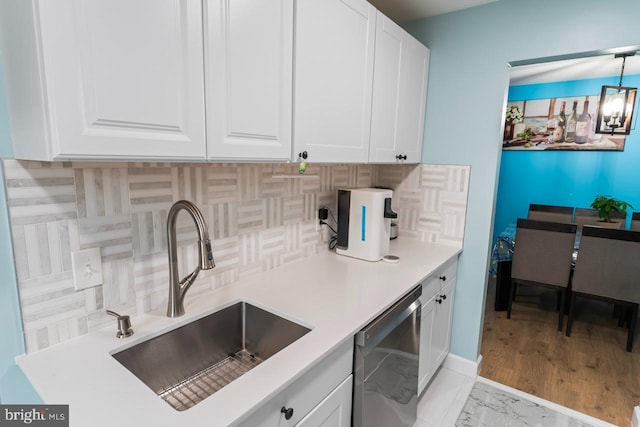 kitchen featuring decorative backsplash, dishwasher, a sink, light countertops, and white cabinetry