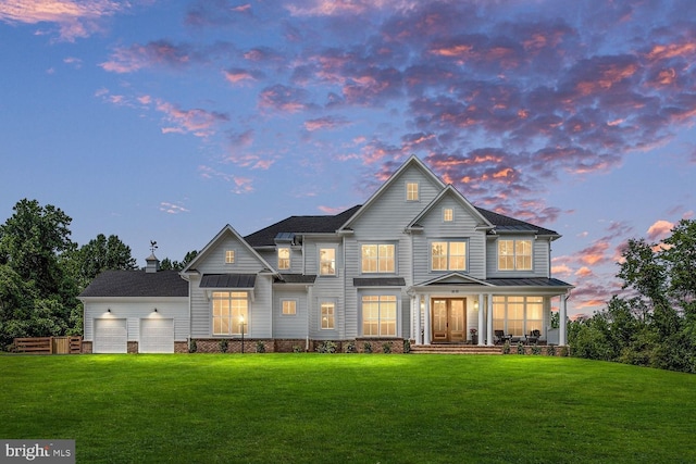 back of house featuring a lawn, covered porch, and an attached garage