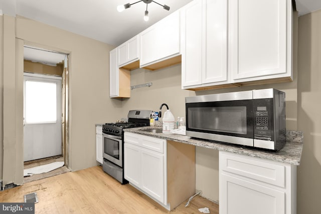 1222 18th St NE, Washington, DC 20002 - kitchen featuring white cabinets, light stone counters, a sink, light wood finished floors, and appliances with stainless steel finishes