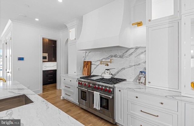 76 Filly Ln, Lewes, DE 19958 - kitchen with double oven range, premium range hood, white cabinetry, decorative backsplash, and recessed lighting