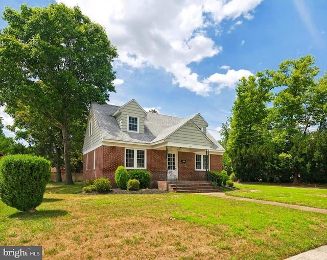 new england style home with a porch, brick siding, and a front lawn