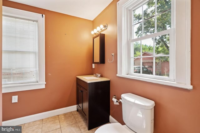half bath with baseboards, tile patterned flooring, vanity, and toilet