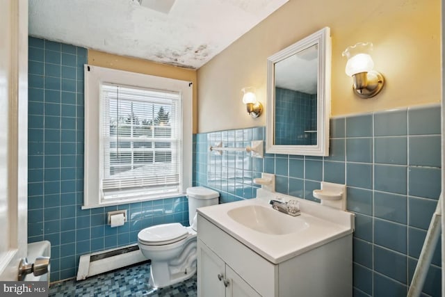half bath with vanity, tile walls, a baseboard heating unit, and toilet