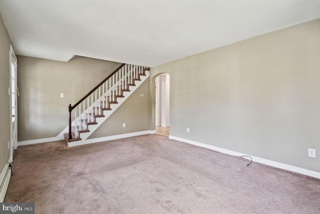 unfurnished living room with stairway, carpet floors, baseboards, and arched walkways