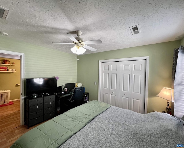 bedroom featuring ceiling fan, a closet, wood finished floors, and visible vents