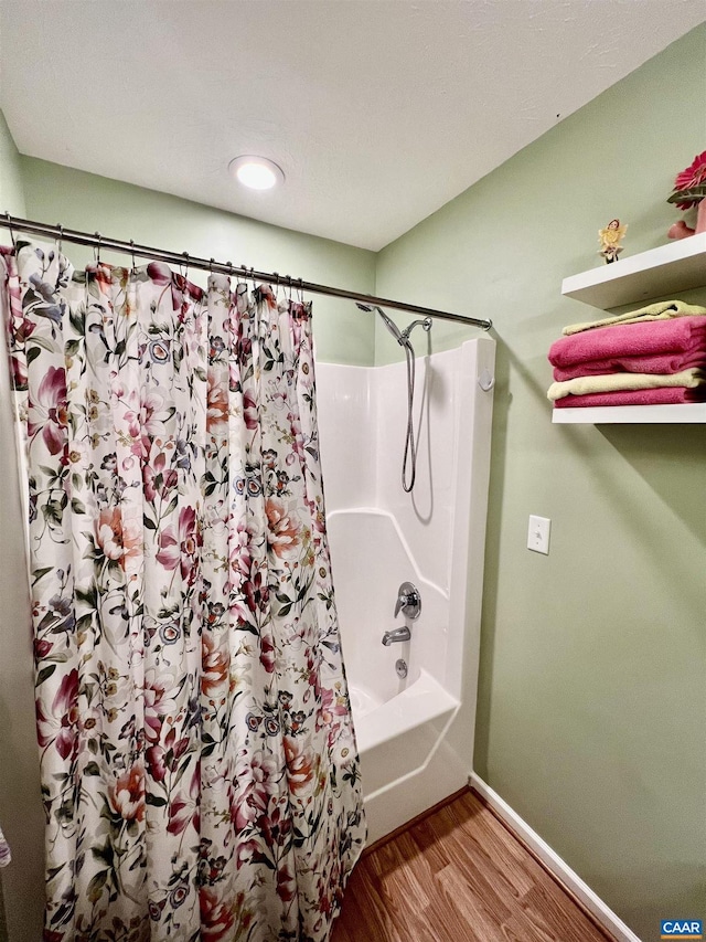 bathroom featuring baseboards, shower / tub combo with curtain, and wood finished floors