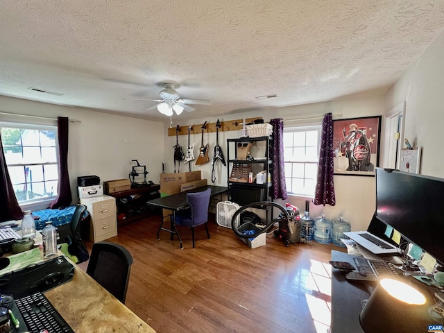 office area featuring a textured ceiling, ceiling fan, wood finished floors, and a healthy amount of sunlight