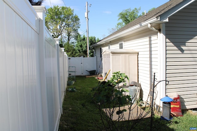 view of property exterior featuring a fenced backyard, a yard, a storage shed, and a shingled roof