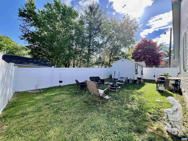 view of yard featuring an outdoor structure, a fire pit, and a fenced backyard