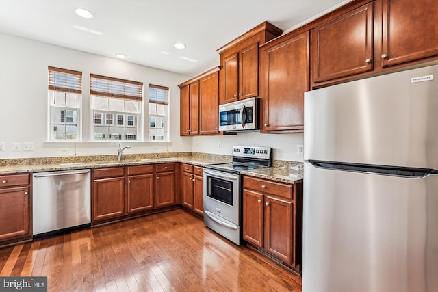 8210 Heritage Crossing Ct, Manassas, VA 20109 - kitchen featuring stainless steel appliances, light stone countertops, dark wood finished floors, brown cabinetry, and a sink