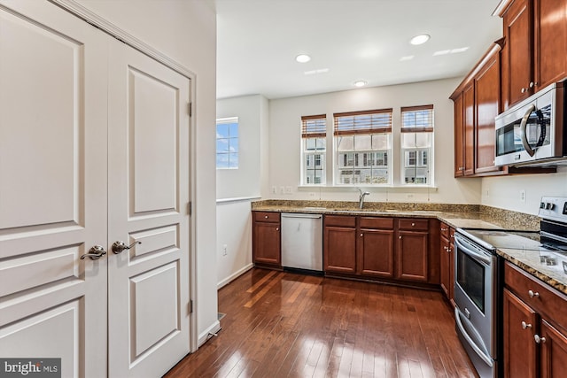 8210 Heritage Crossing Ct, Manassas, VA 20109 - kitchen with appliances with stainless steel finishes, dark stone countertops, a sink, dark wood-style floors, and brown cabinetry