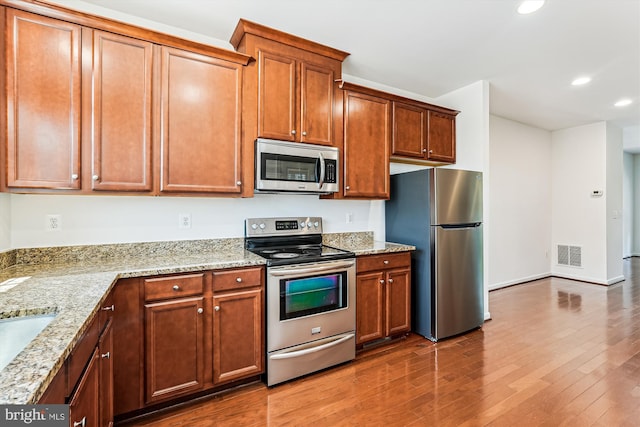 8210 Heritage Crossing Ct, Manassas, VA 20109 - kitchen with stainless steel appliances, recessed lighting, dark wood finished floors, light stone counters, and brown cabinets