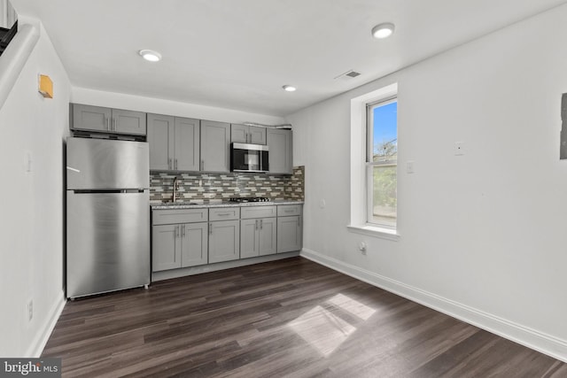 kitchen featuring gray cabinetry, appliances with stainless steel finishes, a sink, and visible vents