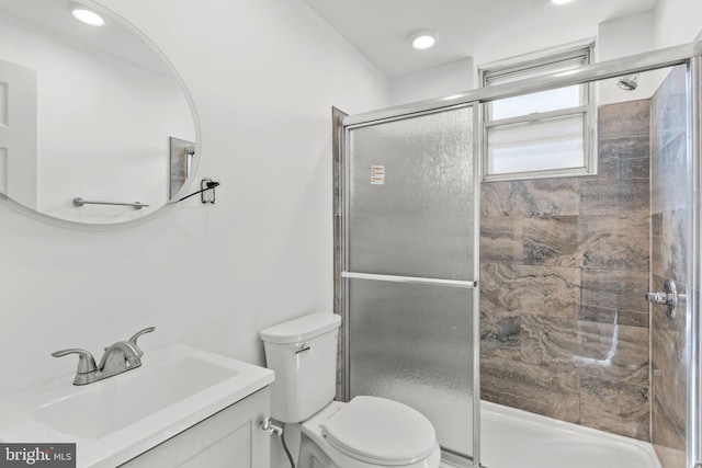 bathroom featuring vanity, a shower stall, and toilet