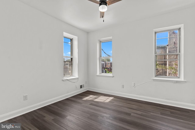empty room with baseboards, a ceiling fan, dark wood finished floors, and visible vents