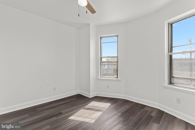 unfurnished room with baseboards, a ceiling fan, and dark wood-type flooring