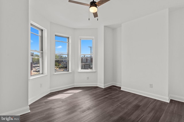 empty room with baseboards, ceiling fan, and dark wood-style floors