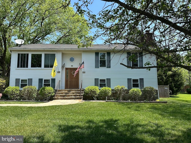 split foyer home with entry steps, a chimney, and a front yard