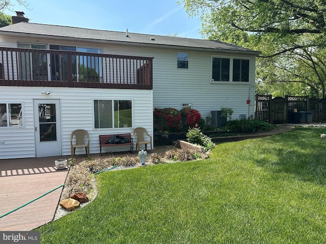rear view of property featuring a chimney, central AC unit, a gate, fence, and a yard