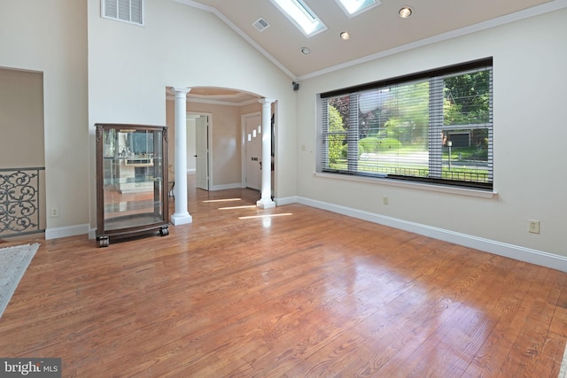 unfurnished living room with crown molding, arched walkways, ornate columns, and visible vents