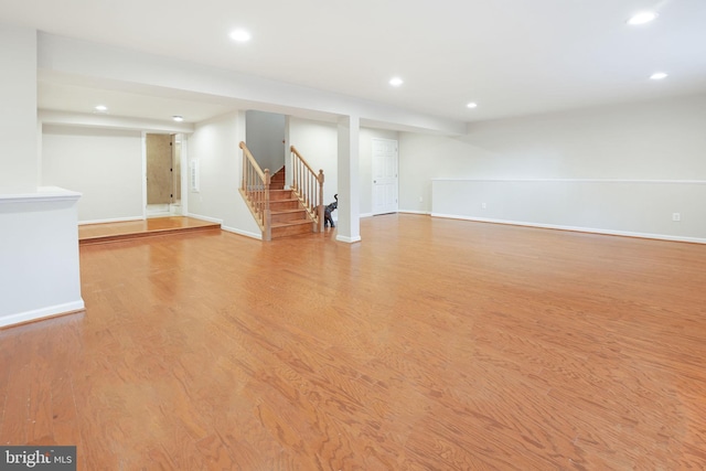 finished basement with recessed lighting, stairs, light wood finished floors, and baseboards