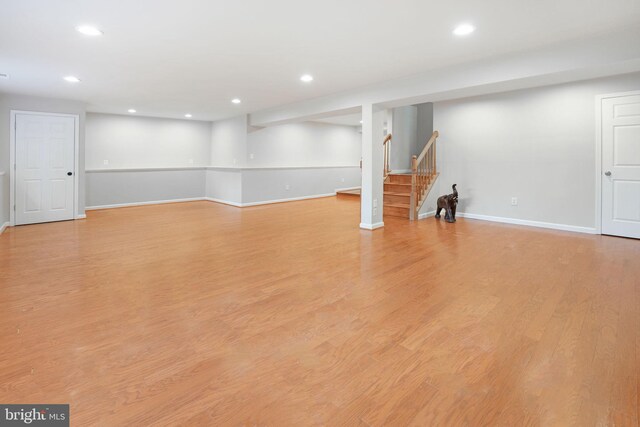 finished below grade area featuring stairs, recessed lighting, baseboards, and light wood-type flooring