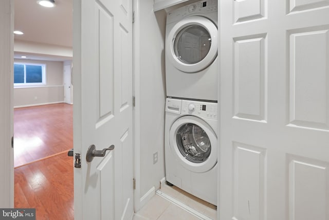 laundry room featuring laundry area, stacked washer / drying machine, light wood-type flooring, baseboards, and recessed lighting