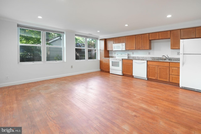 kitchen with a sink, baseboards, light wood-style floors, and white appliances