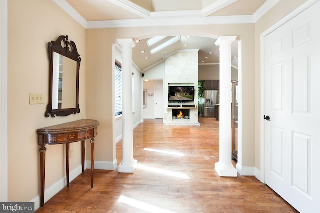 hall with crown molding, light wood finished floors, and ornate columns