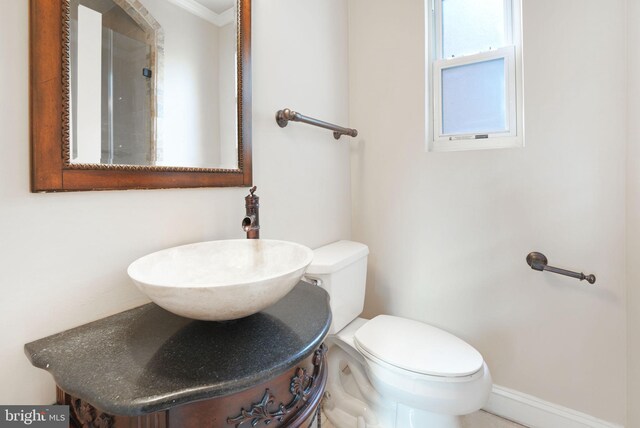 bathroom featuring crown molding, a sink, baseboards, and toilet