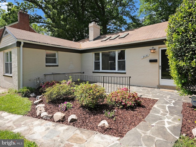 view of front of home featuring brick siding, a patio area, and a chimney
