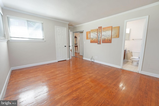 unfurnished bedroom with baseboards, ornamental molding, light wood finished floors, and ensuite bath