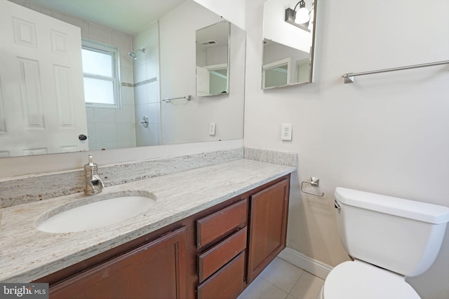 full bath with a tile shower, vanity, toilet, tile patterned floors, and baseboards