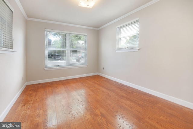 spare room featuring baseboards, ornamental molding, and light wood finished floors