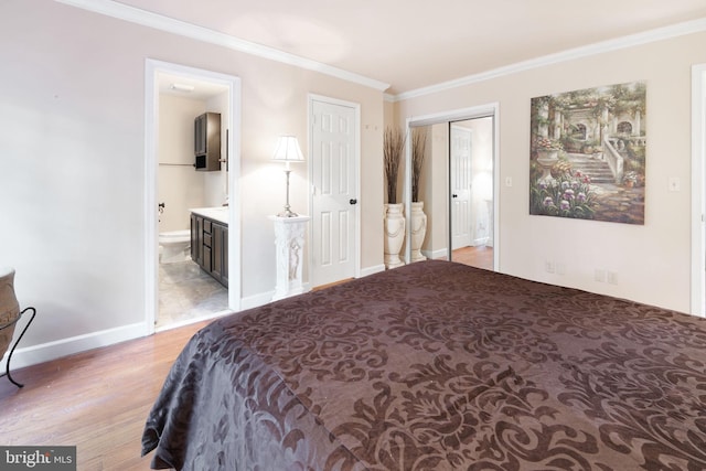 bedroom featuring crown molding, baseboards, light wood-style flooring, and ensuite bath
