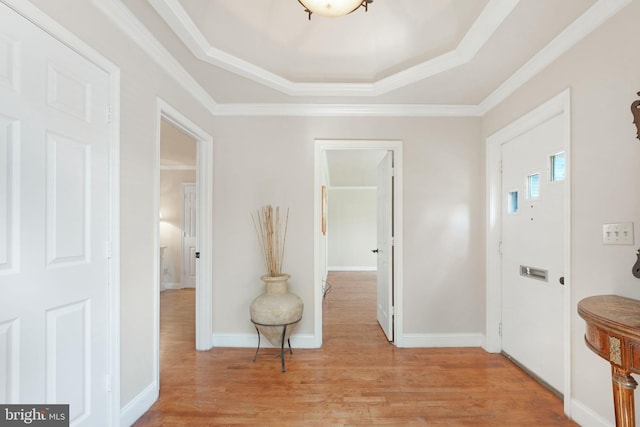entryway featuring light wood-style floors, a raised ceiling, crown molding, and baseboards