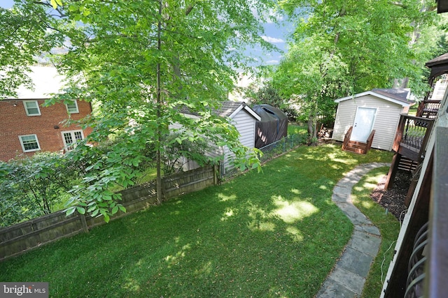 view of yard with a fenced backyard, a shed, an outbuilding, and a wooden deck