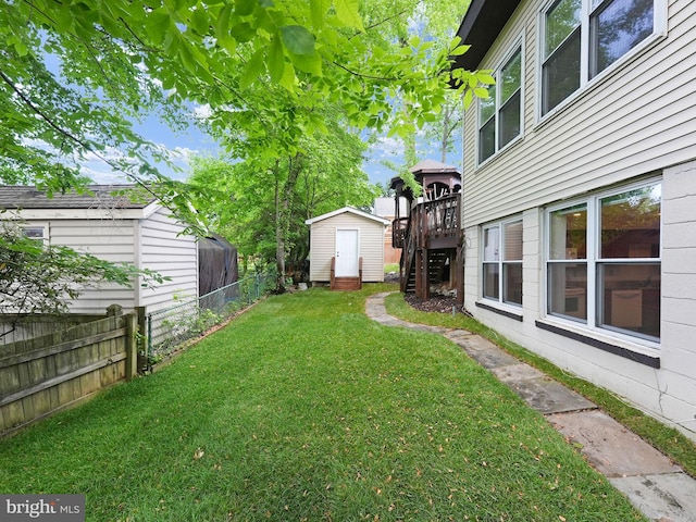 view of yard with fence, a storage unit, a wooden deck, stairway, and an outdoor structure