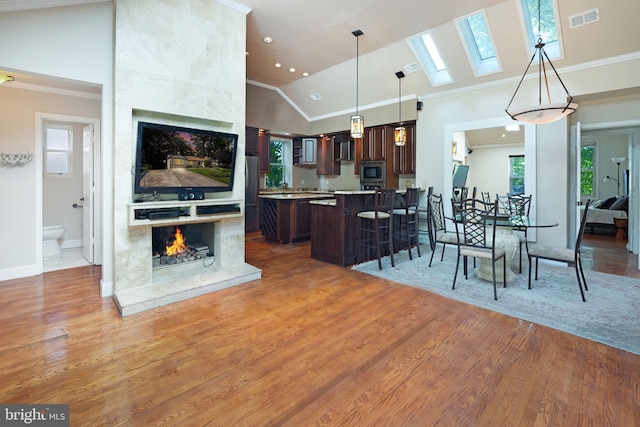 kitchen with visible vents, dark brown cabinetry, wood finished floors, a fireplace, and stainless steel microwave