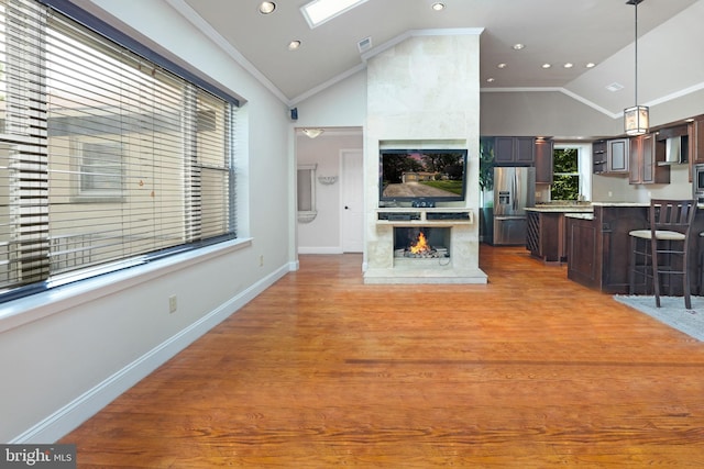 living room with crown molding, baseboards, lofted ceiling, a tile fireplace, and visible vents