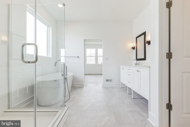 full bathroom with vanity, baseboards, a freestanding tub, visible vents, and a stall shower