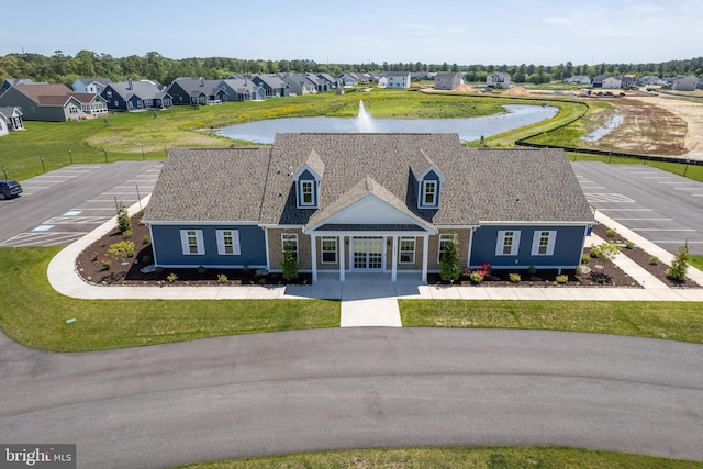 exterior space with a water view, a front lawn, and a residential view