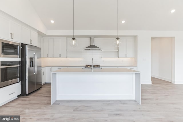 kitchen featuring wall chimney range hood, light countertops, white cabinets, backsplash, and stainless steel appliances