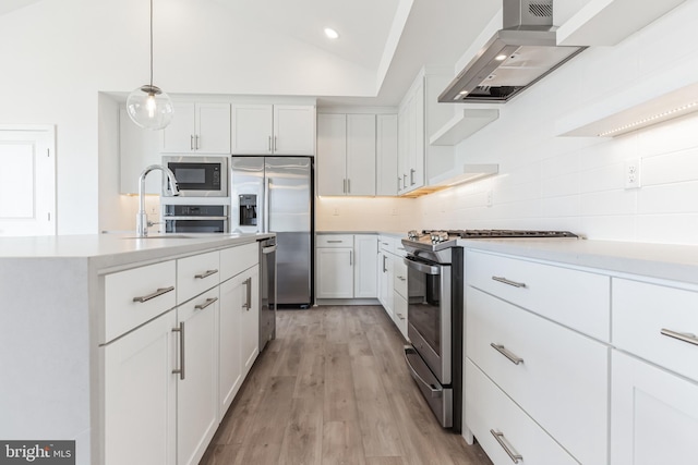 kitchen with decorative backsplash, appliances with stainless steel finishes, a sink, light countertops, and wall chimney exhaust hood