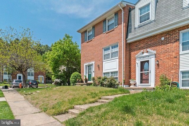 view of front of property featuring brick siding and a front lawn
