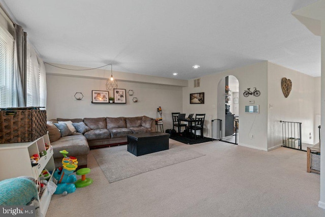 living area with arched walkways, carpet floors, baseboards, and recessed lighting
