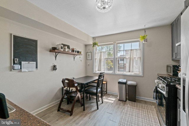 dining area featuring light wood finished floors, baseboards, and a chandelier