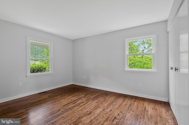 unfurnished room with plenty of natural light, wood finished floors, and baseboards