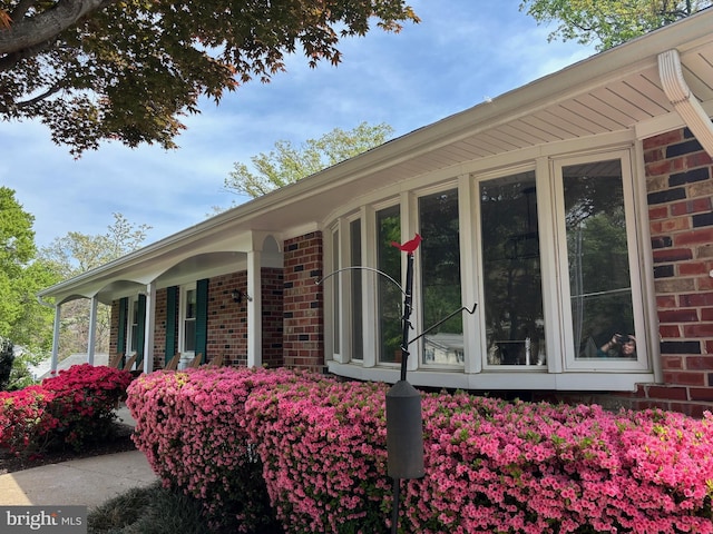view of side of home featuring brick siding and a porch