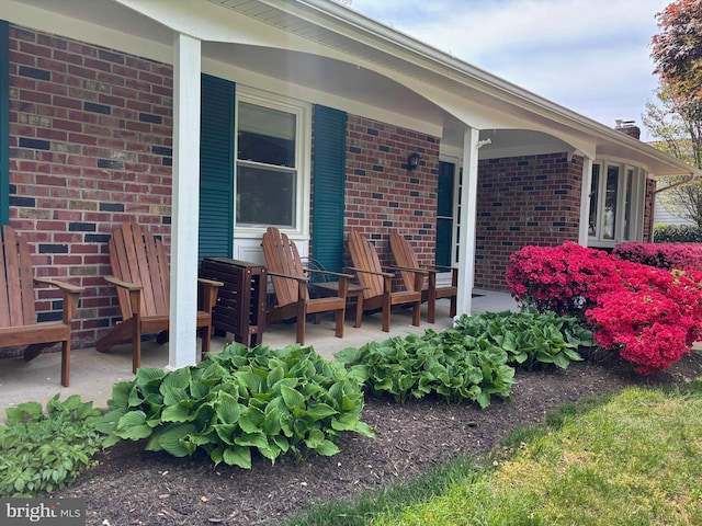 view of exterior entry featuring brick siding and a porch